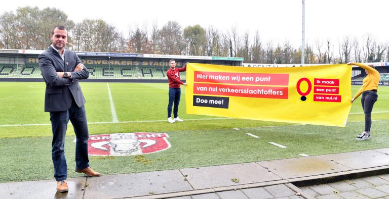 Twee mensen van FC Dordrecht houden een spandoek vast met "Hier maken wij een punt van nul verkeersslachtoffers - doe mee"
