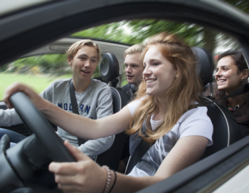 Een groep kinderen kijkt mee terwijl een meisje de auto bestuurd